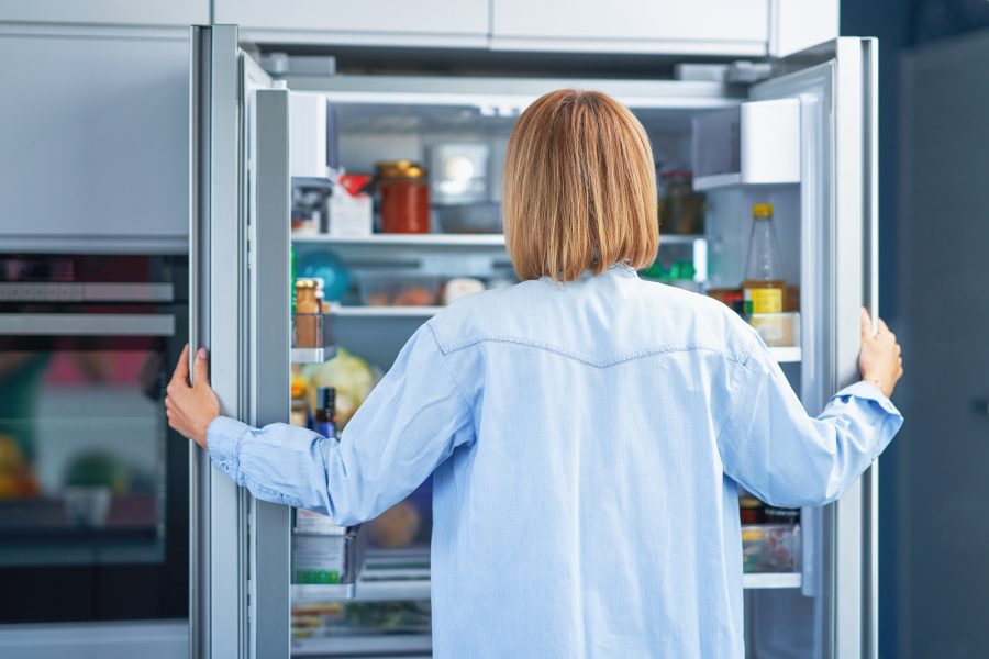 Young adult woman in the kitchen with the fridge